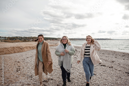 Happy multicultural friends have fun , laugh and hug each other in the sea. People walking together, the beautiful plus size woman with girls are smiling.