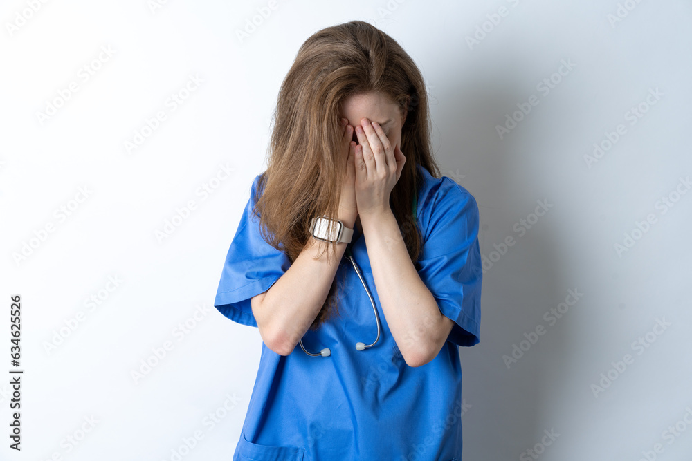 Young caucasian doctor woman wearing medical uniform covering her face with her hands, being devastated and crying. Sad concept Young caucasian doctor woman wearing medical uniform covering her face with her hands, being devastated and crying. Sad concept