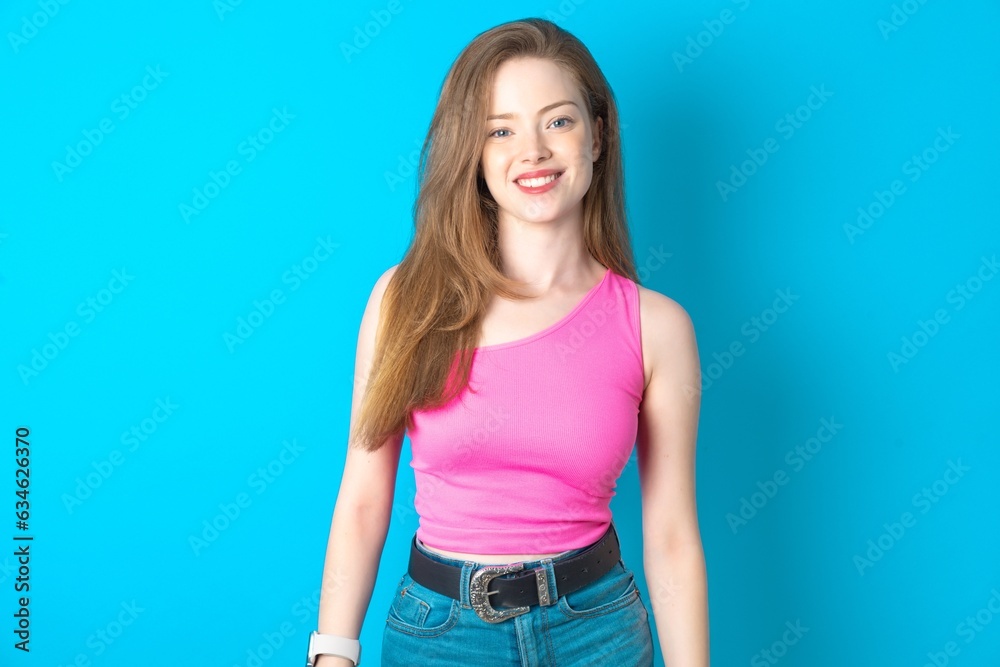 Young beautiful girl wearing pink T-shirt with nice beaming smile pleased expression. Positive emotions concept Young beautiful girl wearing pink T-shirt with nice beaming smile pleased expression. Positive emotions concept