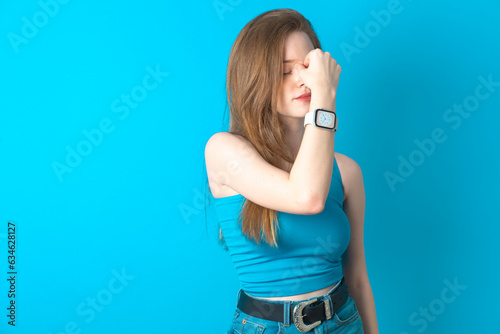 Sad Young beautiful girl wearing blue T-shirt suffering from headache holding hand on her face