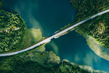 Aerial view of bridge asphalt road with cars and blue water lake and green woods in Finland.