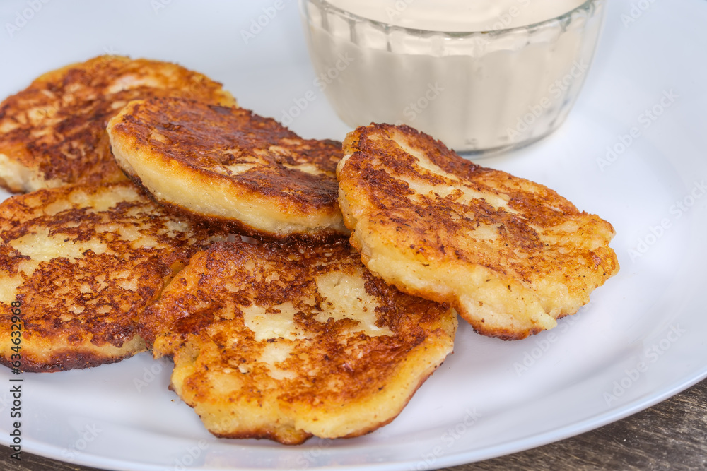 Сottage cheese pancakes with sour cream on dish close-up