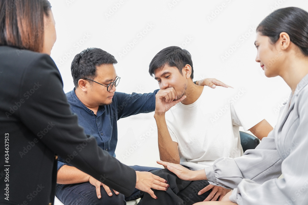 Group of Diverse asian people supporting desperate unhappy man. Depressed male patient suffering from bullying, sharing personal problems at psychological therapy group meeting. Group of Diverse asian people supporting desperate unhappy man. Depressed male patient suffering from bullying, sharing personal problems at psychological therapy group meeting.