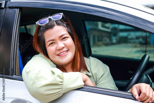Portrait of a fat Asian woman driving a car, smiling happily. Asian tourists. Travel concept, transportation. Car insurance.
