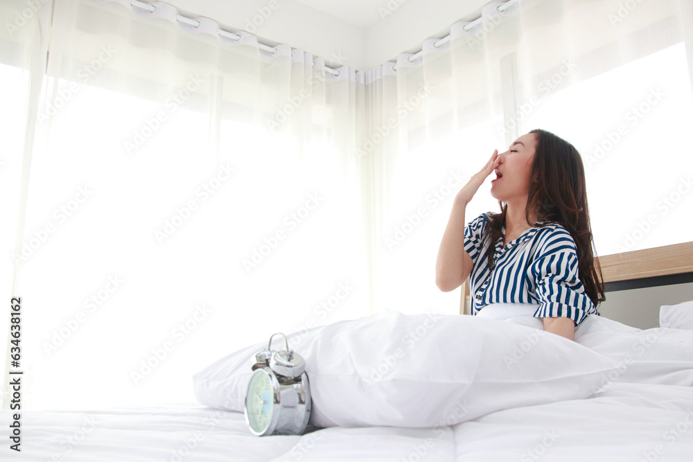 Beautiful Asian woman sitting on the bed She yawned when she woke up in the morning. health concept. copy space Beautiful Asian woman sitting on the bed She yawned when she woke up in the morning. health concept. copy space