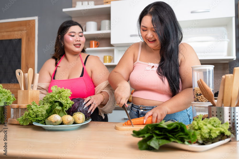 Happy Asia plus size woman cooking salad in kitchen at home
