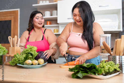 Happy Asia plus size woman cooking salad in kitchen at home