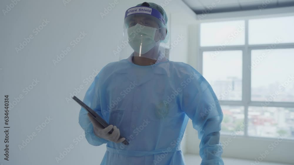 A doctor with a tablet in his hands walks along the hospital corridor. The doctor walks along the corridor of the modern clinic. A doctor in a protective suit A doctor with a tablet in his hands walks along the hospital corridor. The doctor walks along the corridor of the modern clinic. A doctor in a protective suit