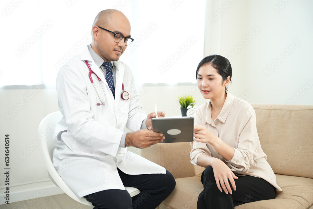 Smiley beautiful asian women patient consulting with Handsome asian professional doctor feeling happy about good news and The doctor writing and analyzing her symptoms on the tablet. Smiley beautiful asian women patient consulting with Handsome asian professional doctor feeling happy about good news and The doctor writing and analyzing her symptoms on the tablet.