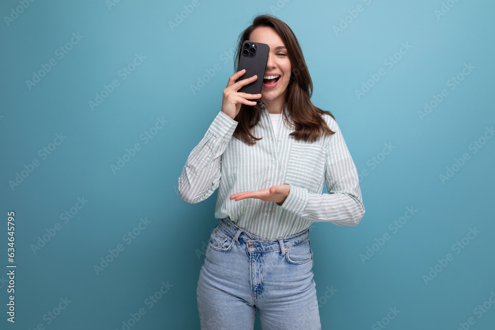 cute young brunette woman in a shirt makes a photo on a smartphone on a studio background cute young brunette woman in a shirt makes a photo on a smartphone on a studio background