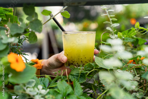 Close-up of a woman standing outdoors holding a green kiwi and basil muddled cocktail