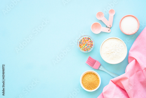 Food baking background on blue. Ingredients for cooking, flour, sugar, eggs. Flat lay with copy space.