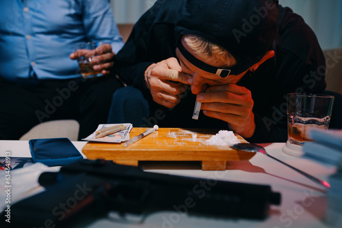 Criminal in black hoodie snorting line of cocaine photo