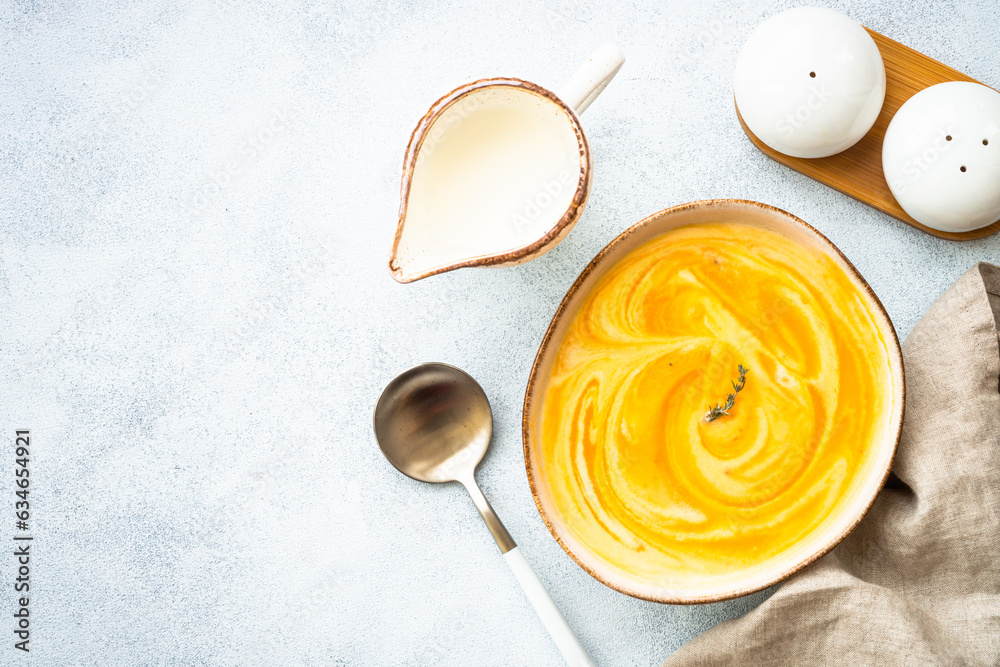 Pumpkin soup with cream in the craft bowl at stone table. Healthy eating. Top view with copy space. Pumpkin soup with cream in the craft bowl at stone table. Healthy eating. Top view with copy space.