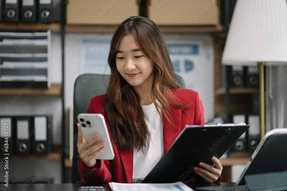 Business women hand working with smartphone and laptop computer with documents on office desk in modern office. Business women hand working with smartphone and laptop computer with documents on office desk in modern office.