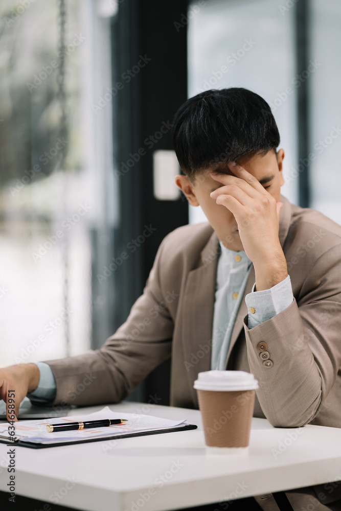 Sad businessman is sitting at table, covering his face with his hand. On desk is laptop, tablet computer, Stress. Sad businessman is sitting at table, covering his face with his hand. On desk is laptop, tablet computer, Stress.