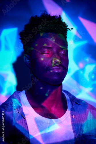 Photos Calm black man standing with eyes closed in neon lights