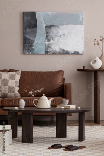 Warm composition of cozy living room interior with mock up poster frame, brown sofa, wooden coffee table, slippers, simple console, chess prints rug and personal accessories. Home decor. Template.