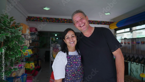 Joyful Couple Owners of Small Business smiling and laughing together while standing in front of storefront. Authentic real life people entrepreneurs of PetShop