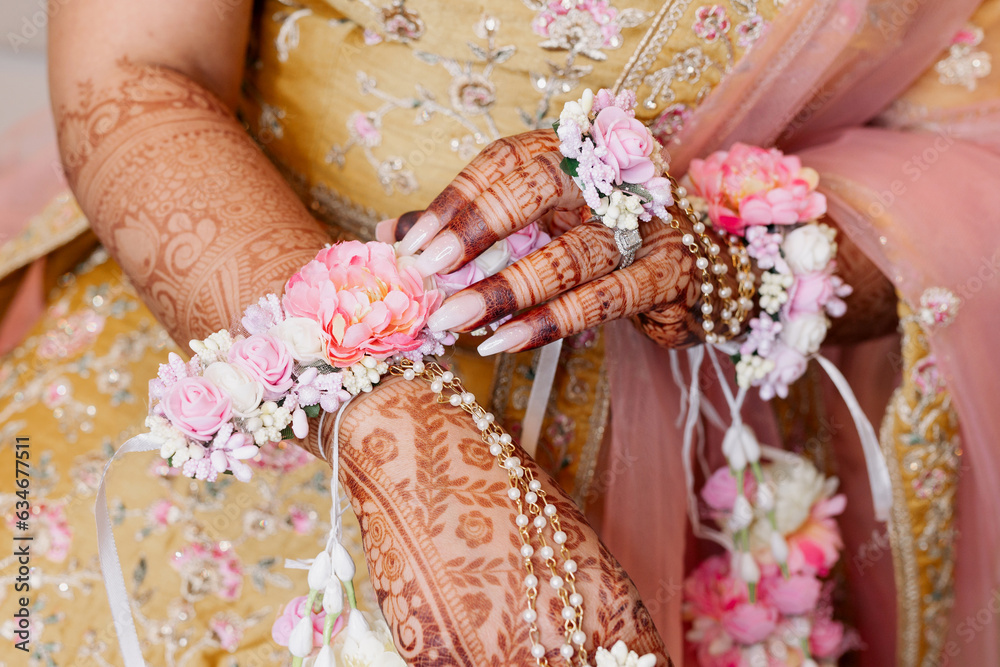 Fototapeta premium The hands of an Indian bride are decorated with Indian-style henna flowers and patterns. Hands of the bride close-up with patterns and ornaments in traditional Indian style top view patterns