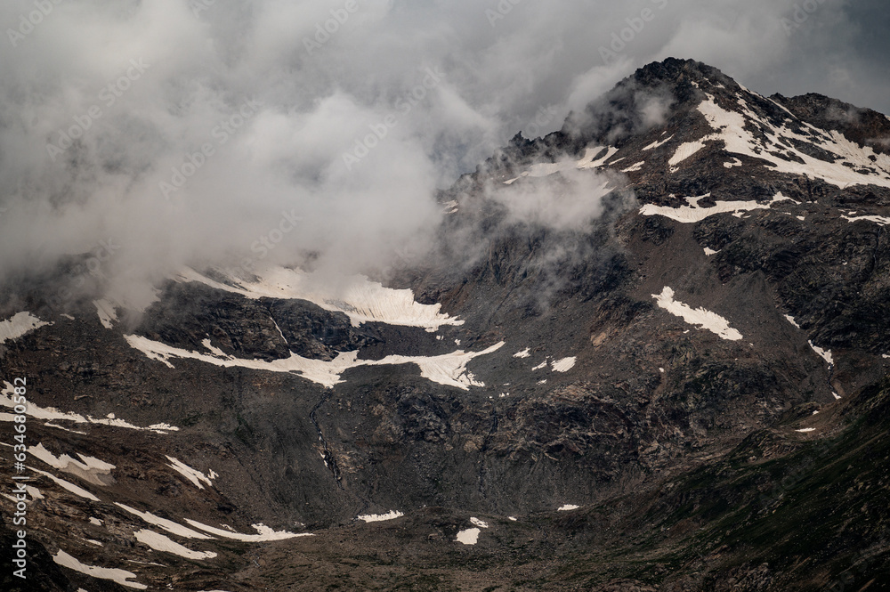gloomy atmospheric rocks, dark mountains covered with clouds and puffs of fog. Mountain peak of snow-capped mountains, beautiful panorama of mountains. dark high rocks