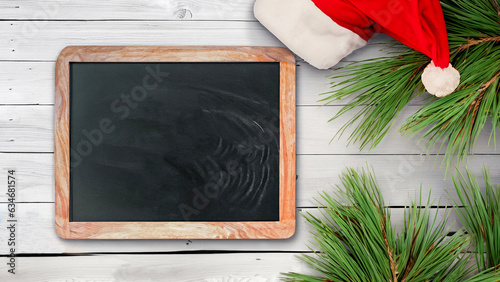 happy new year holiday greeting card.Chalkboard, pine branches and santa hat on rustic white wooden table texture1, copy space photo