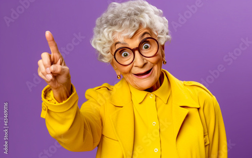 Smiling elderly woman points to the empty space next to her - isolated on violet background
