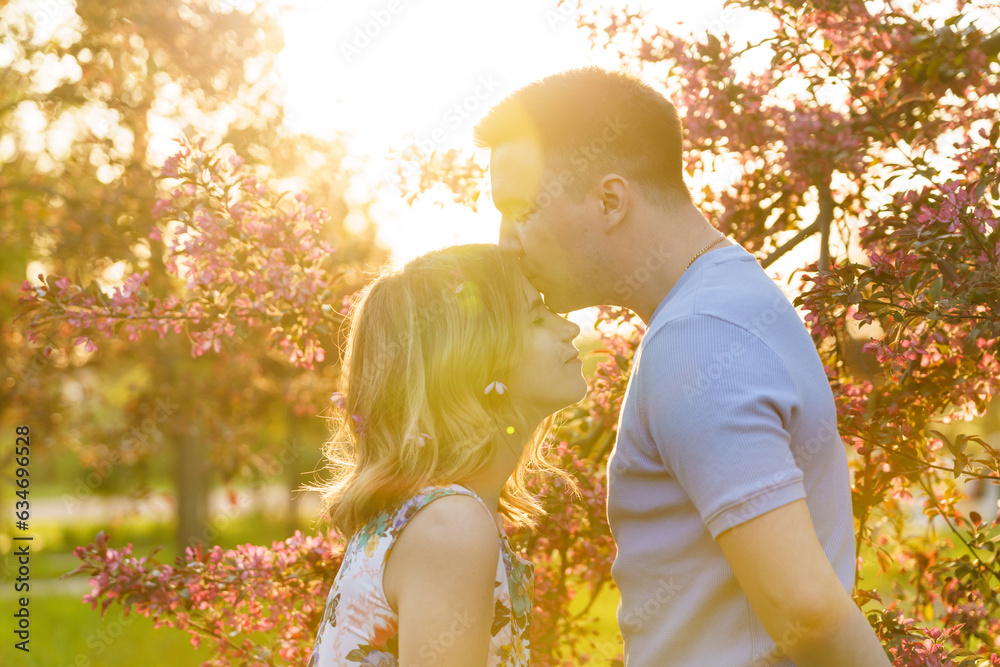 Young couple guy kisses girl's forehead in a blooming apple orchard. The concept of healthy relationships, partnership, the psychology of healthy relationships and support Young couple guy kisses girl's forehead in a blooming apple orchard. The concept of healthy relationships, partnership, the psychology of healthy relationships and support