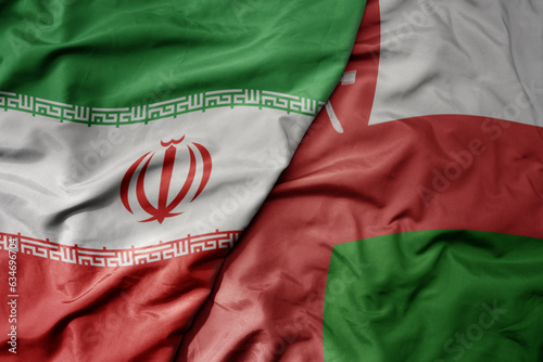 big waving realistic national colorful flag of iran and national flag of oman .