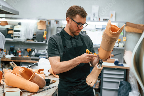 Tightening the screws. Technician working with prosthesis in modern laboratory