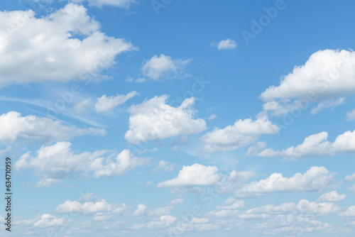 Blue cloudy sky with many beautiful white fluffy cumulus clouds in sunlight background texture