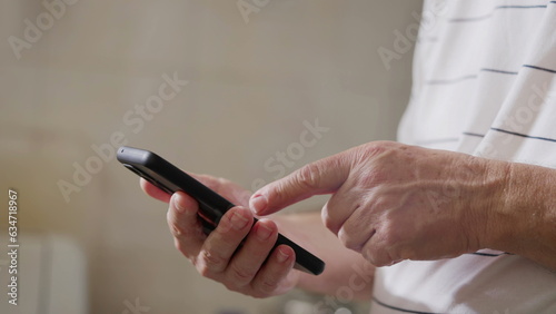 Close-up senior man hands holding cellphone device gesturing. Older person hand and finger pointing at screen  elderly individual using modern technology