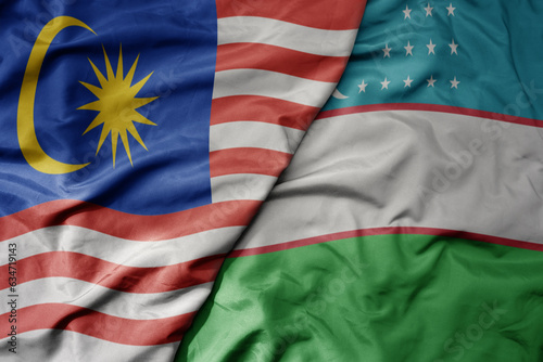 big waving realistic national colorful flag of malaysia and national flag of uzbekistan .