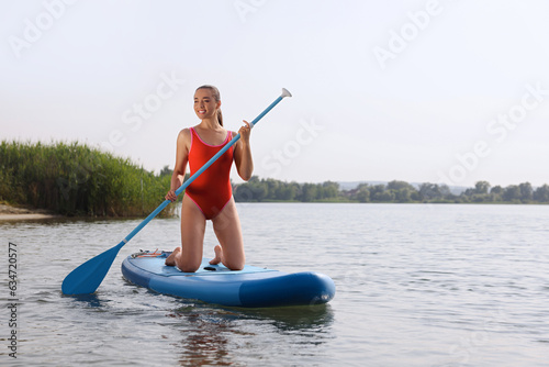 Woman paddle boarding on SUP board in sea, space for text © New Africa