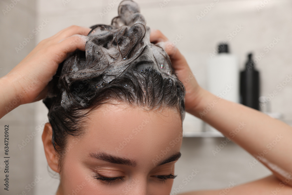 Naklejka premium Woman washing hair with shampoo in shower, closeup