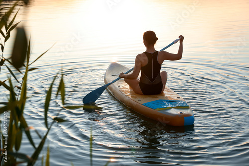 Woman paddle boarding on SUP board in river at sunset, back view © New Africa