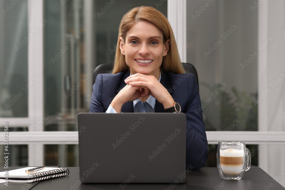 Woman working on laptop at black desk in office