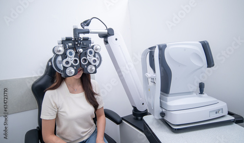 Woman optical shop customer doing eyesight measurement with optical phoropter check eye distance for eyeglasses is optical eye shop service.	 photo