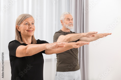 Senior couple practicing yoga at home, selective focus