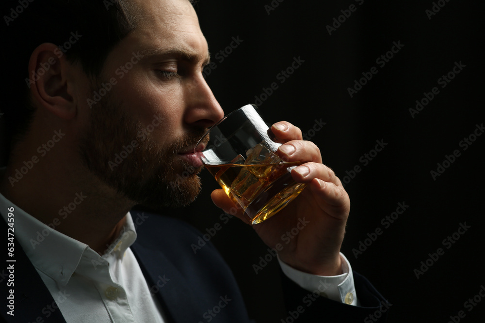 Man in suit drinking whiskey on black background Man in suit drinking whiskey on black background