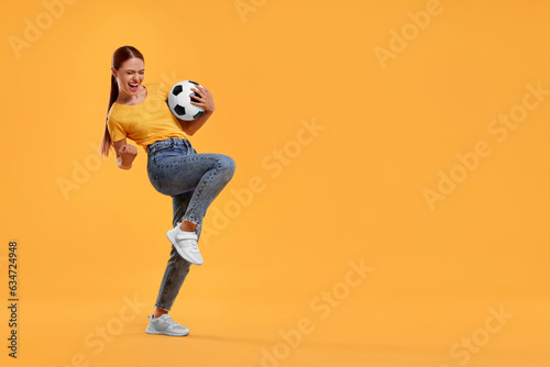 Fototapeta Naklejka Na Ścianę i Meble -  Happy fan with football ball celebrating on yellow background, space for text