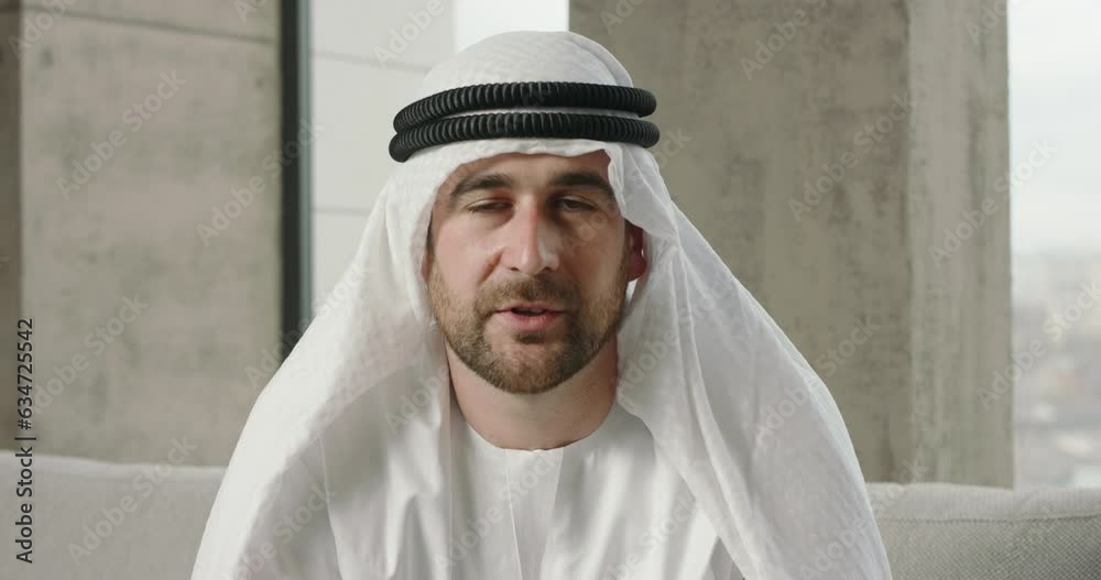 Video call with bearded Arab man. Video meeting with young Arab man in traditional outfit, man is talking speaking. Virtual conference with Arab man sheikh, emloyee, coworker, webcam view portrait. Video call with bearded Arab man. Video meeting with young Arab man in traditional outfit, man is talking speaking. Virtual conference with Arab man sheikh, emloyee, coworker, webcam view portrait.