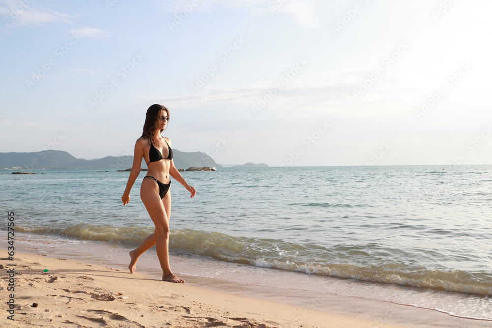 Sexy beautiful young woman posing in black swimwear bikini play  walking  on the sea beach