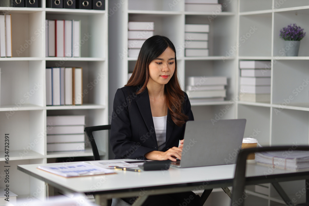 Attractive Asian businesswoman working with laptop and paperwork on office desk. Attractive Asian businesswoman working with laptop and paperwork on office desk.