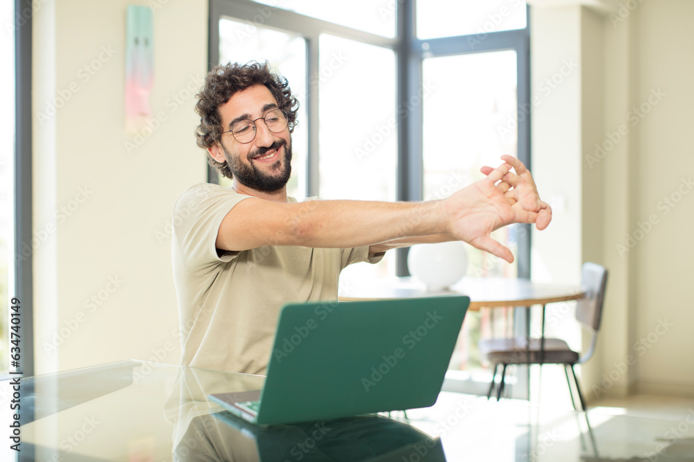 young adult bearded man with a laptop lazily early in the morning, waking and looking sleepy, tired and bored young adult bearded man with a laptop lazily early in the morning, waking and looking sleepy, tired and bored