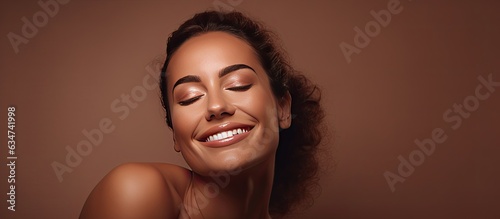 Smiling Brazilian lady performing jade massage on face isolated on brown background beauty care procedure