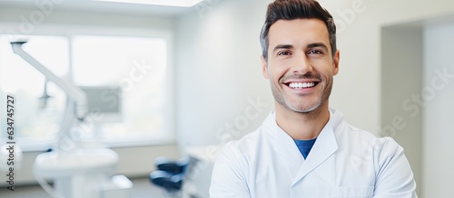 Smiling male dentist holding clipboard in dental clinic interior looking at camera