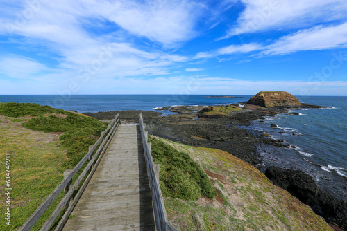 Beautiful blue sky with clouds at Phillips Island, Victoria Australia. Wooden broadwalk to seaside with rocks. Outdoor scenic ocean in a sunny day.