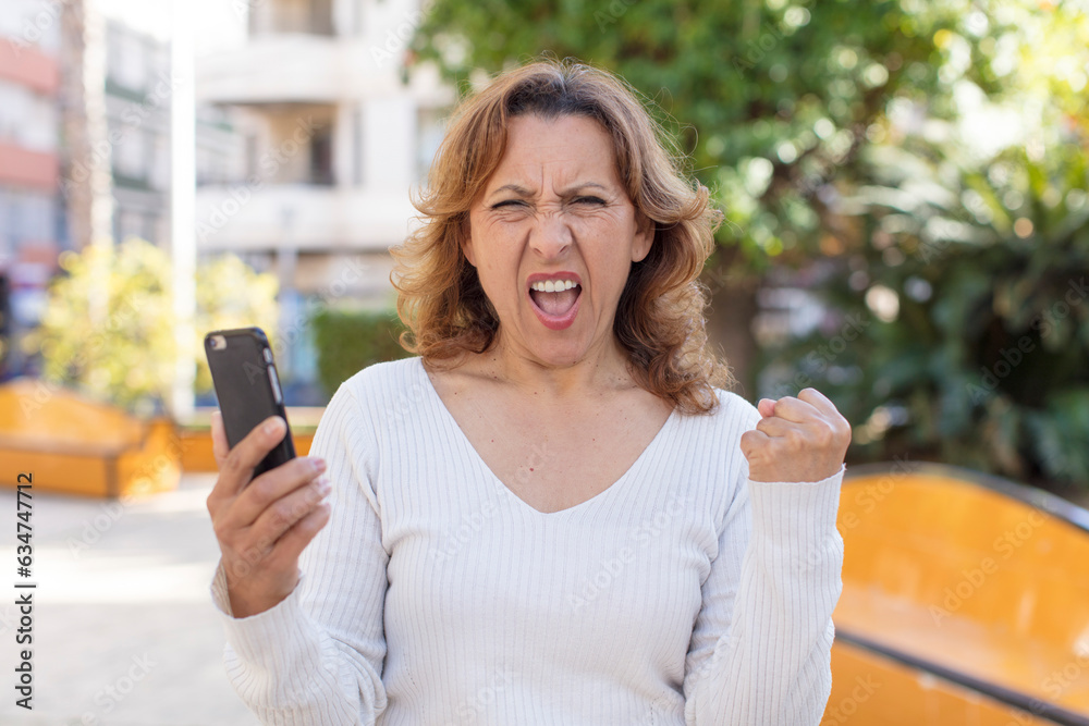 middle age pretty woman looking angry, annoyed and frustrated. using her smartphone middle age pretty woman looking angry, annoyed and frustrated. using her smartphone