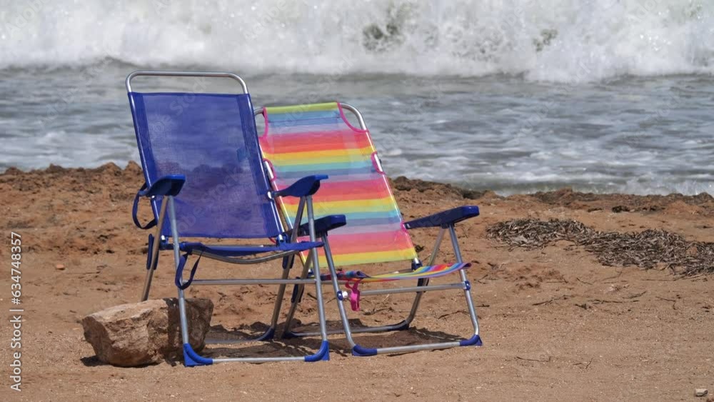 Two vacant sun loungers await on the beach, with languid waves rolling in the backdrop, hinting at relaxation. Two vacant sun loungers await on the beach, with languid waves rolling in the backdrop, hinting at relaxation.